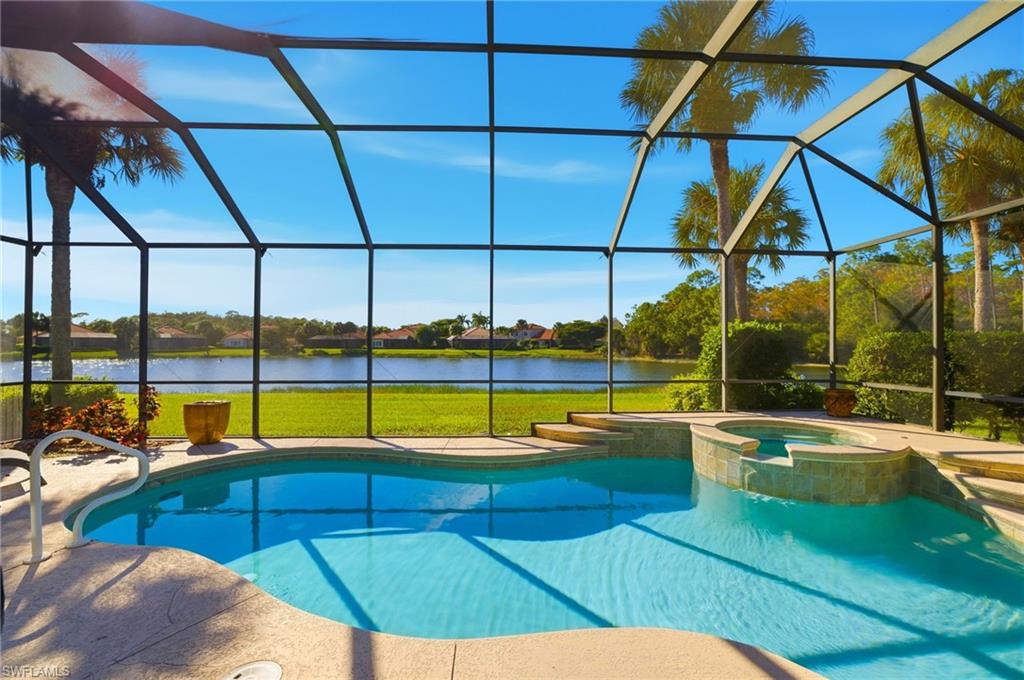 View of swimming pool with a sunroom, a water view, a pool with connected hot tub, a lanai, and a lawn