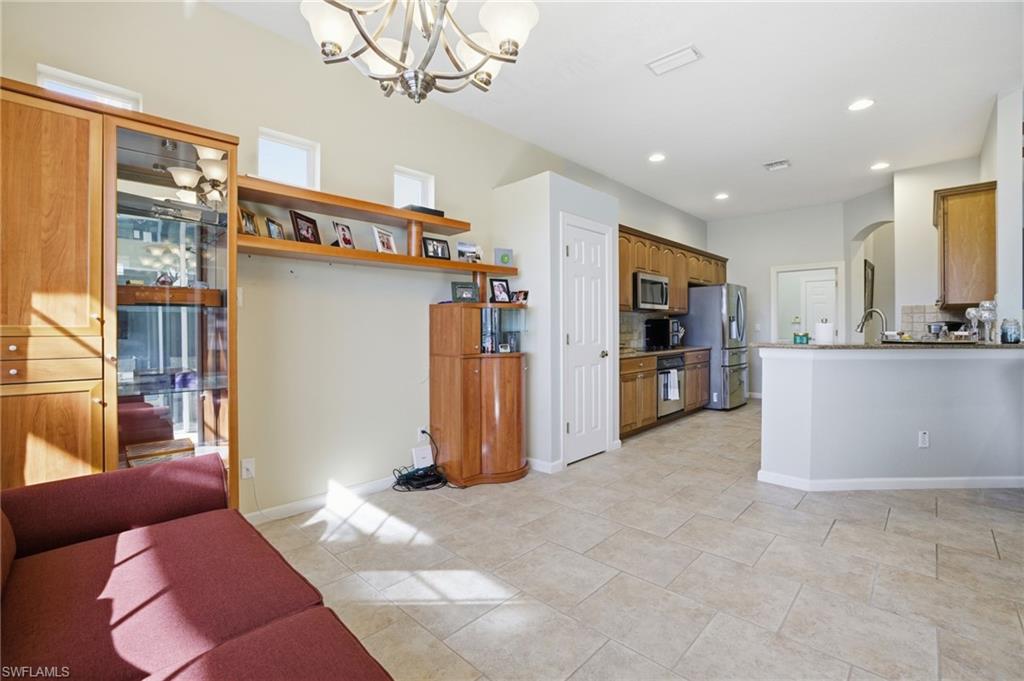 Kitchen featuring arched walkways, brown cabinets, a chandelier, appliances with stainless steel finishes, and backsplash