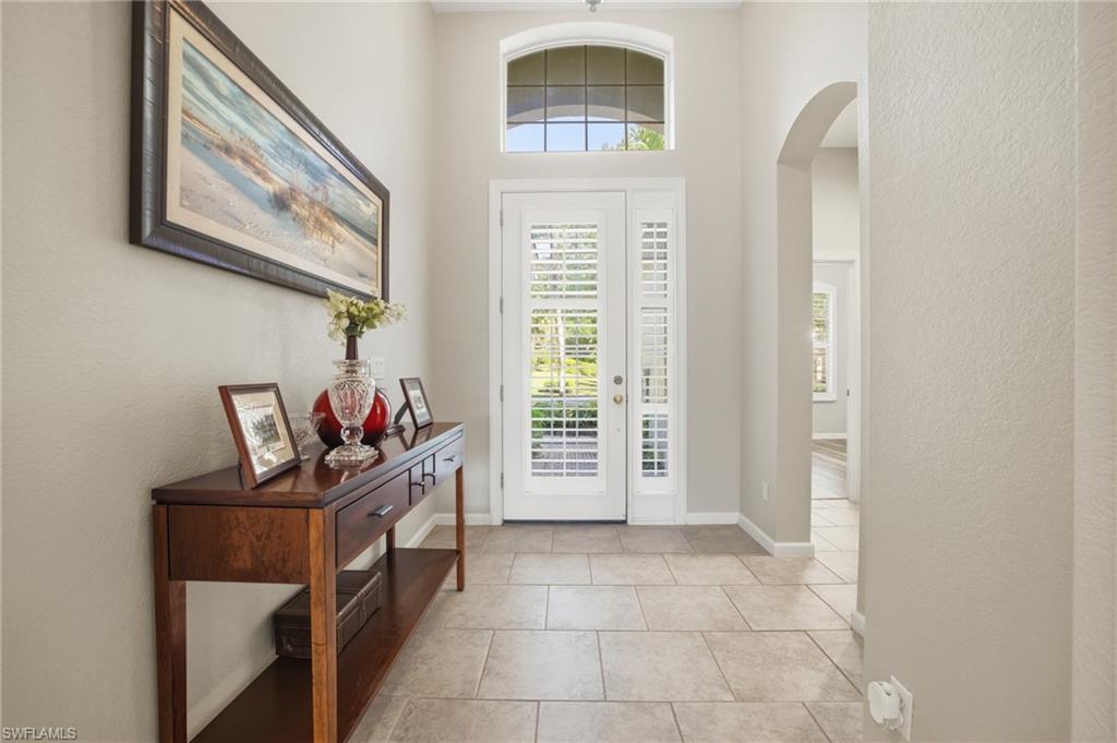 Entryway featuring arched walkways, a textured wall, and light tile patterned floors