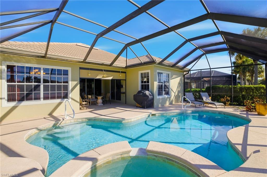View of pool featuring a sunroom, a lanai, a patio, a pool with connected hot tub, and a grill