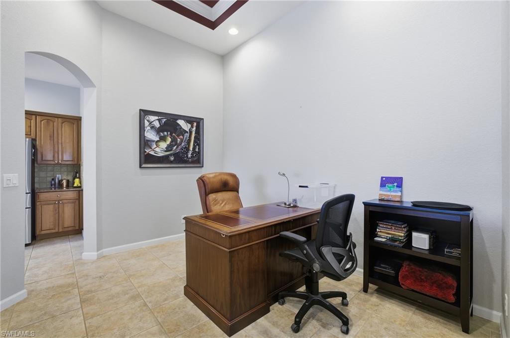 Office space with arched walkways, recessed lighting, and light tile patterned floors