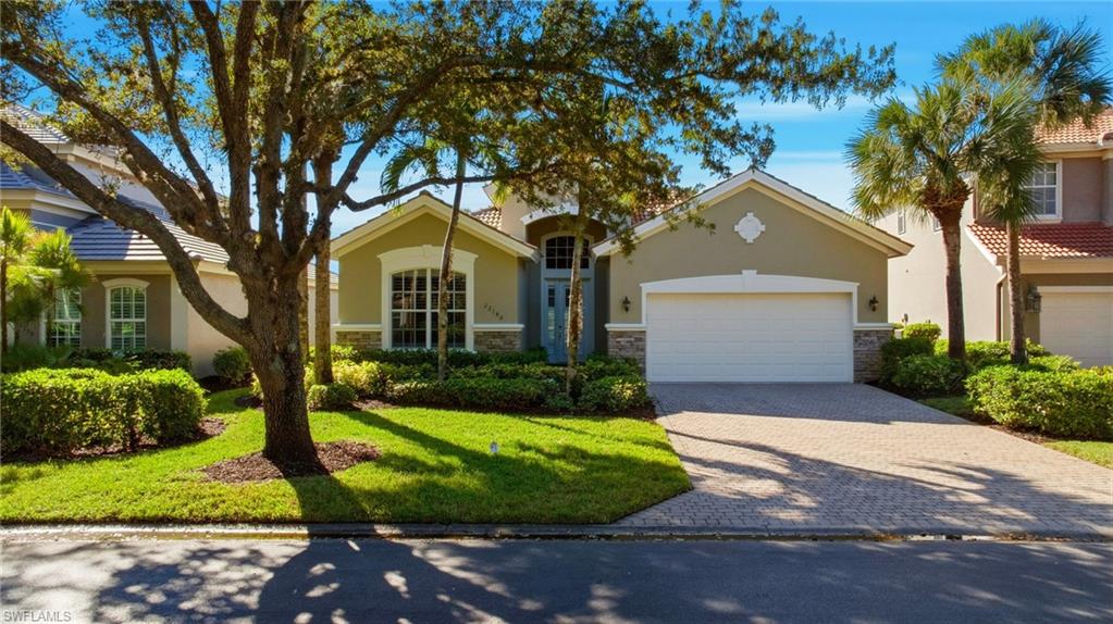 Mediterranean / spanish home with stone siding, decorative driveway, stucco siding, a front lawn, and a garage
