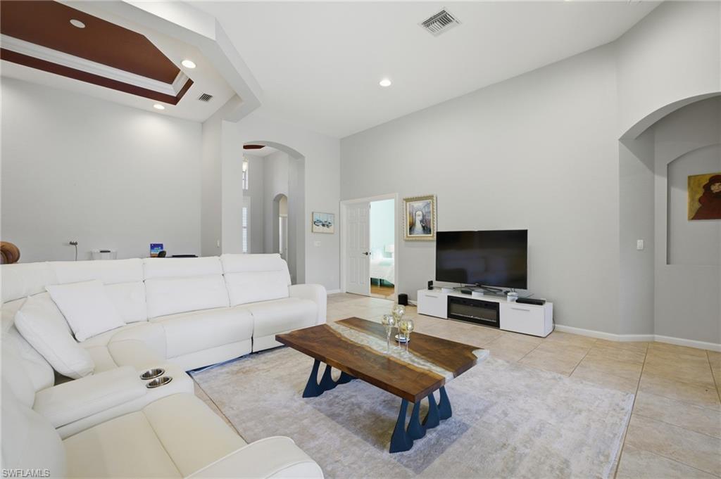Living room featuring arched walkways, light tile patterned flooring, and recessed lighting