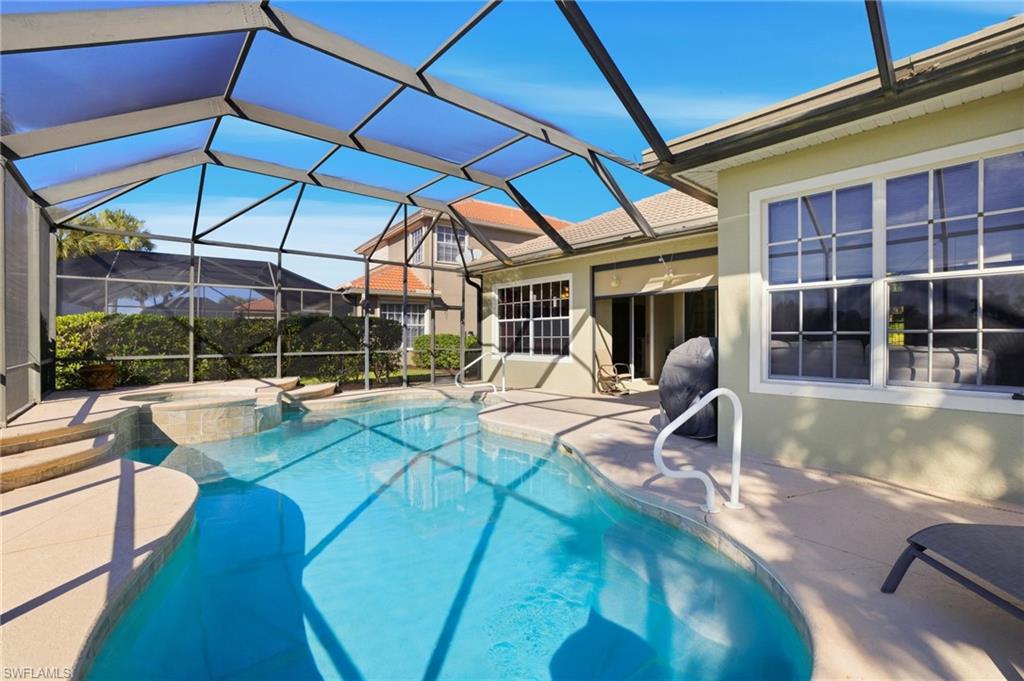View of swimming pool featuring a patio, a sunroom, glass enclosure, and a pool with connected hot tub