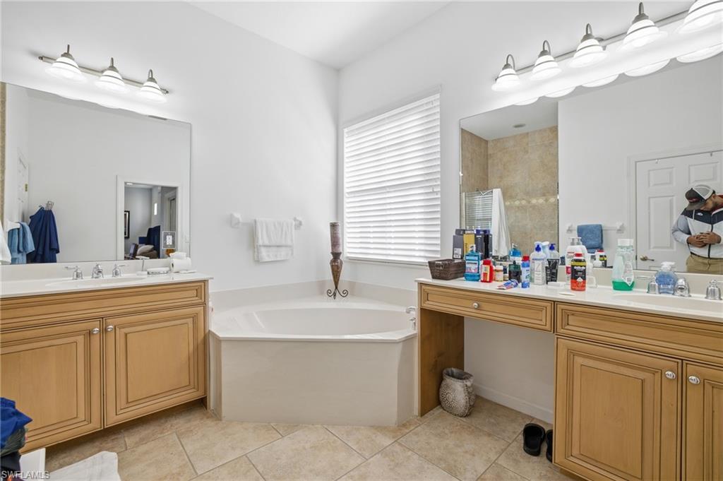 Bathroom with two vanities, a garden tub, light tile patterned floors, and walk in shower