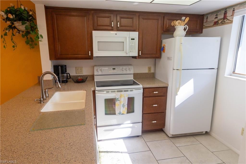 Kitchen with white appliances, brown cabinets, and light tile patterned floors