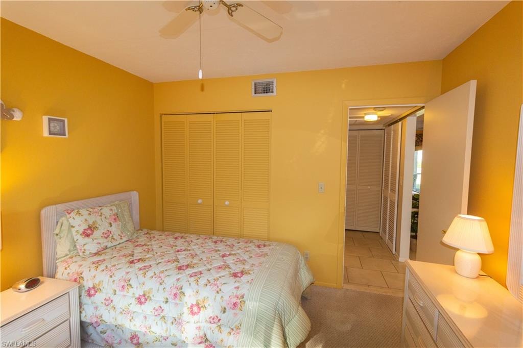 Bedroom featuring a closet, a ceiling fan, light carpet, and light tile patterned floors