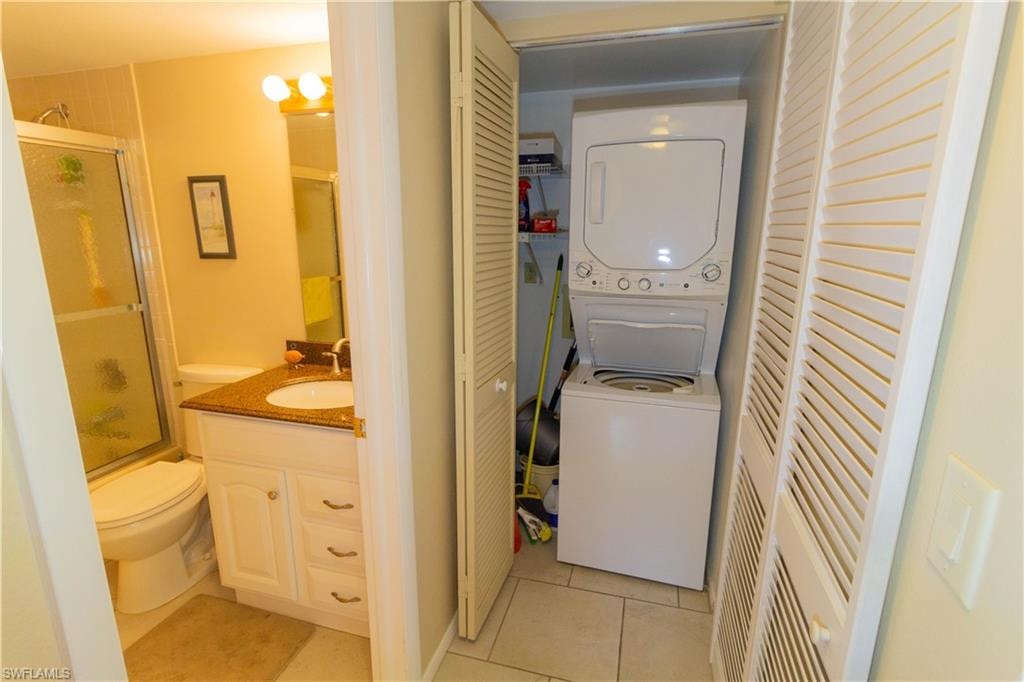 Laundry room with light tile patterned floors and stacked washing machine and dryer