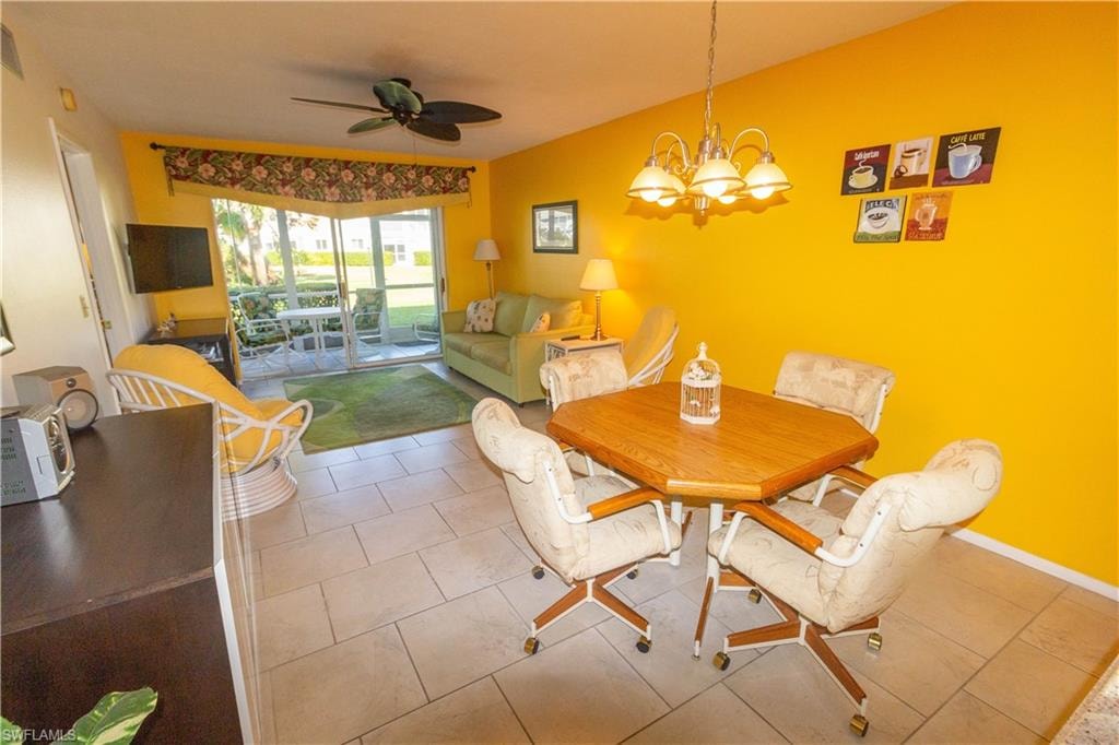 Tiled dining room featuring a ceiling fan and a chandelier