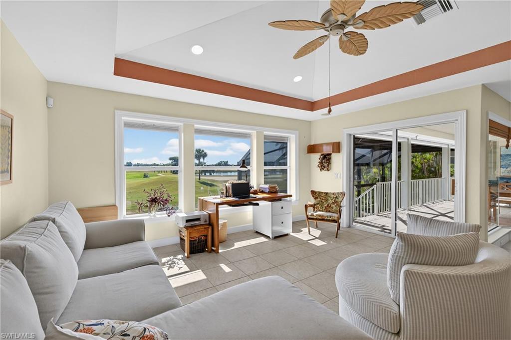Living room featuring tile patterned flooring, ceiling fan, a tray ceiling, recessed lighting, and an office area