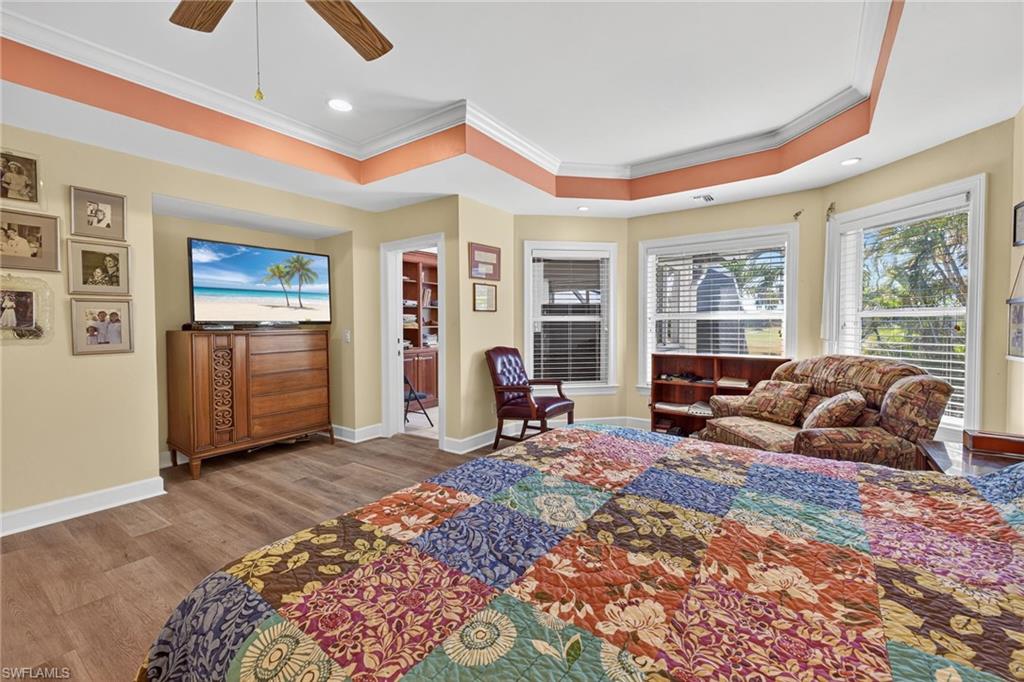 Bedroom featuring wood finished floors, ornamental molding, a ceiling fan, recessed lighting, and a tray ceiling