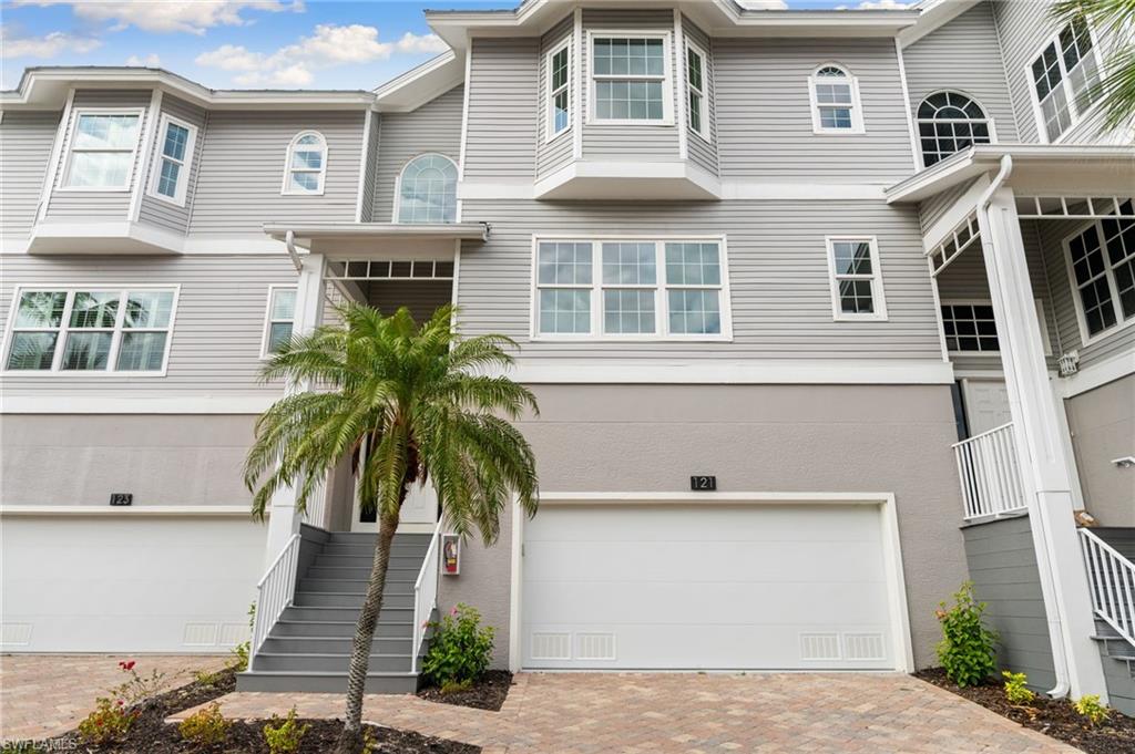 View of front of property with stairway, a garage, and decorative driveway
