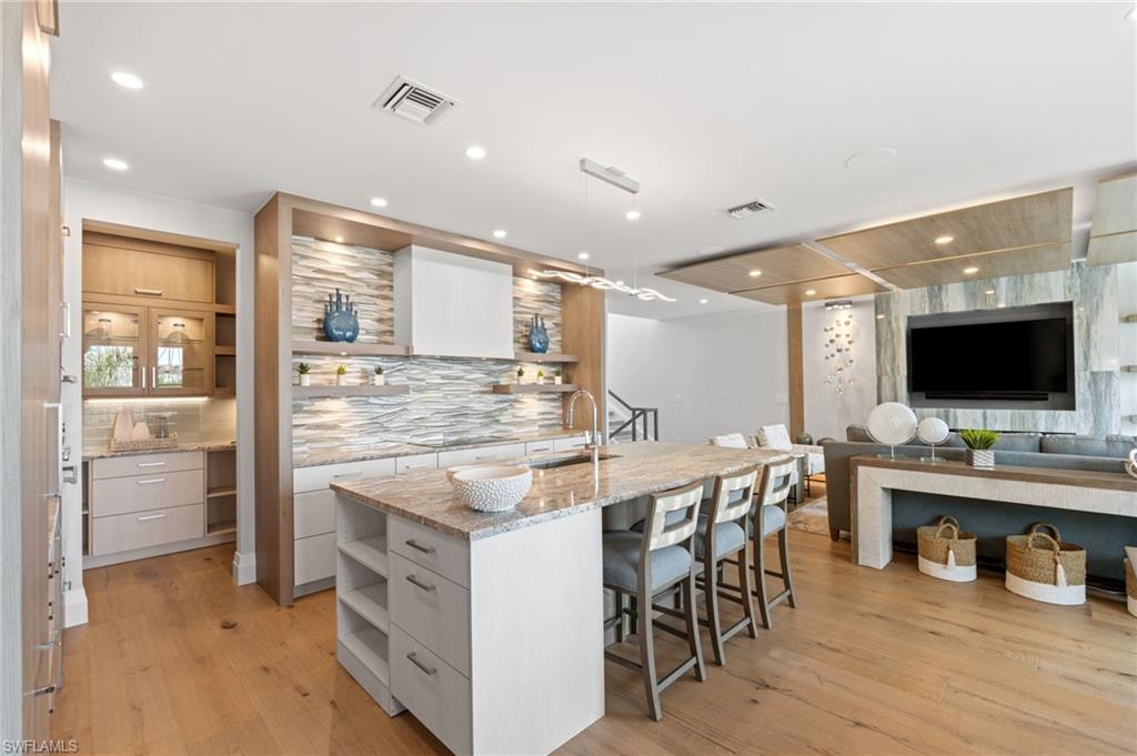 Bar with open shelves, modern cabinets, light stone countertops, white cabinets, and pendant lighting