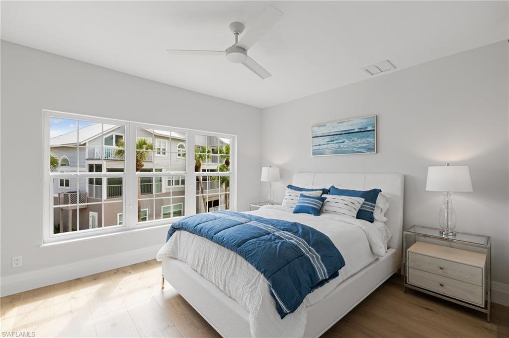 Bedroom featuring ceiling fan, multiple windows, and wood finished floors