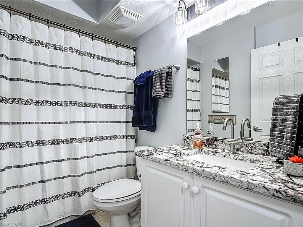 Bathroom featuring vanity, curtained shower, and a textured ceiling