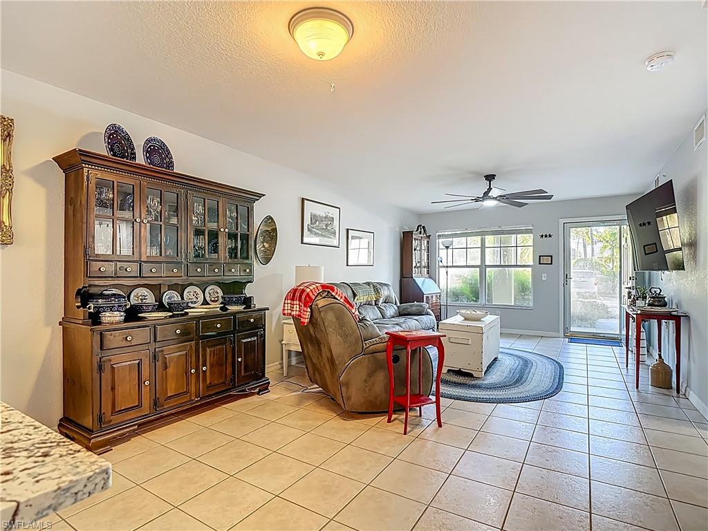 Living area featuring ceiling fan, light tile patterned flooring, and a textured ceiling