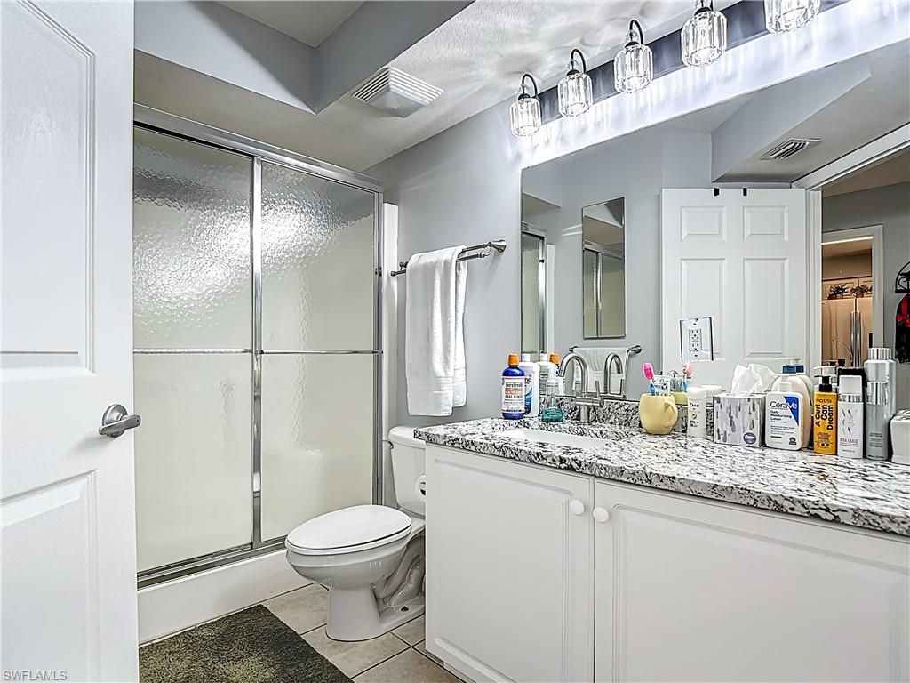 Bathroom featuring a stall shower, vanity, and light tile patterned flooring
