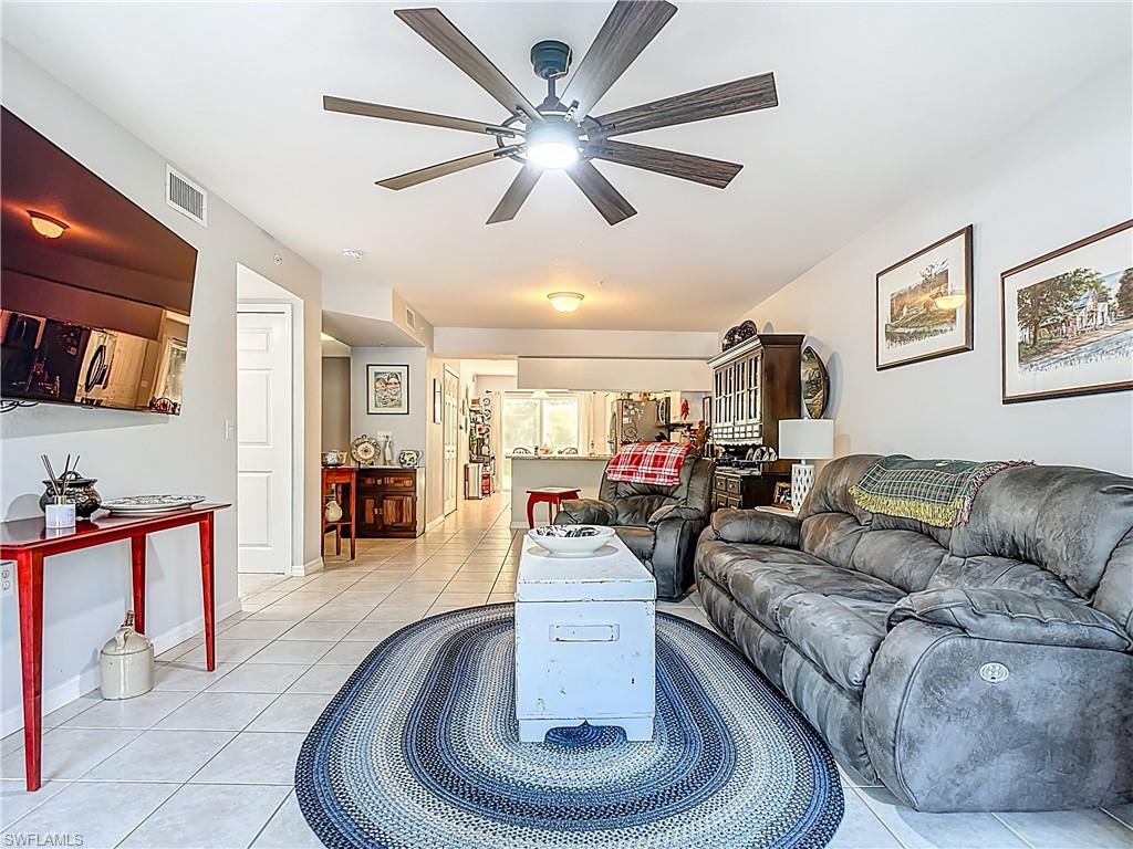 Living room with light tile patterned floors and a ceiling fan
