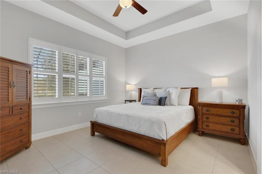 Bedroom featuring a raised ceiling, ceiling fan, and light tile patterned floors