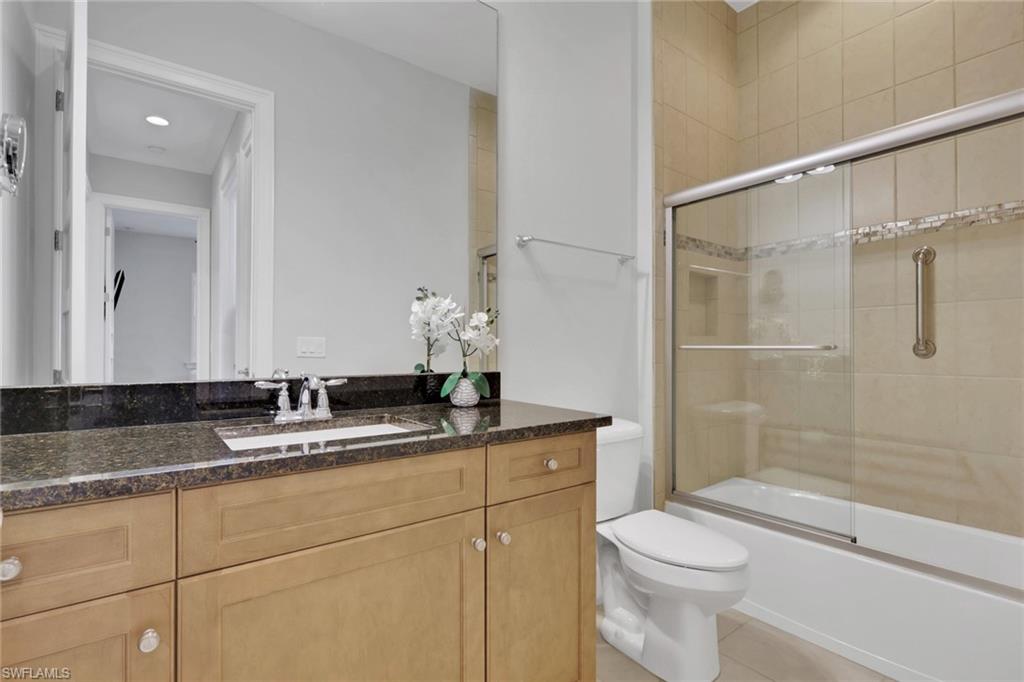 Full bathroom with vanity, shower / bath combination with glass door, and light tile patterned flooring