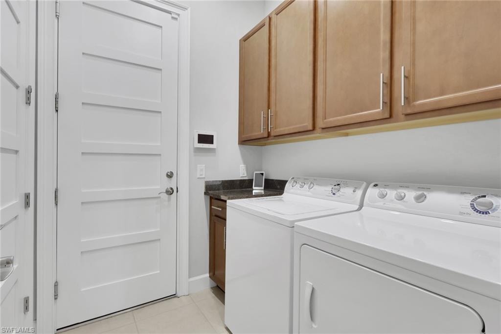Laundry area with light tile patterned flooring, separate washer and dryer, and cabinet space