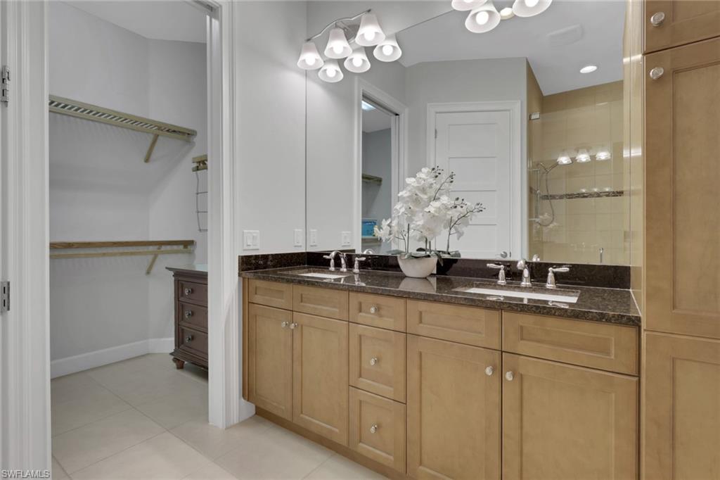 Bathroom featuring double vanity, a shower stall, light tile patterned floors, and a walk in closet