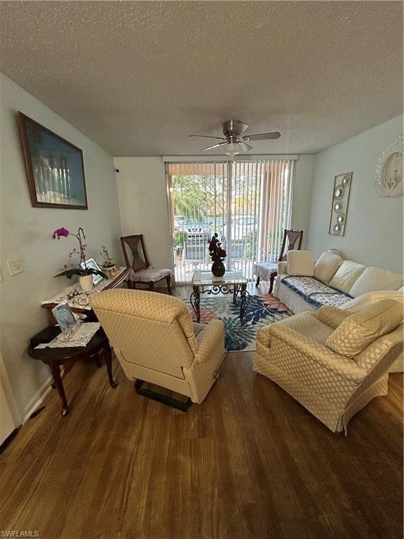 Living area with a textured ceiling, dark wood-style floors, and a ceiling fan