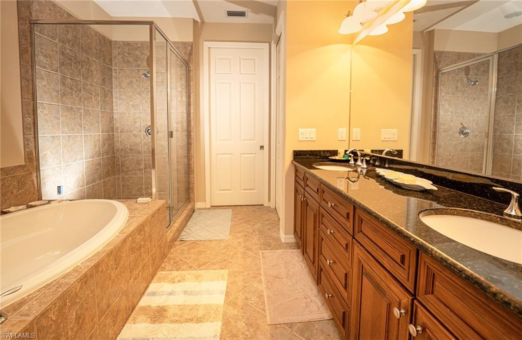 Full bath featuring double vanity, a garden tub, a shower stall, and light tile patterned floors