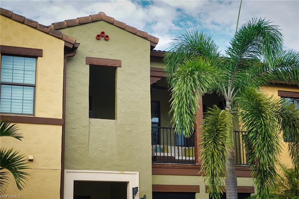 View of side of property with stucco siding, a balcony, and a tile roof