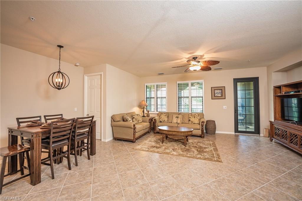 Living room with a textured ceiling, a ceiling fan, and a chandelier