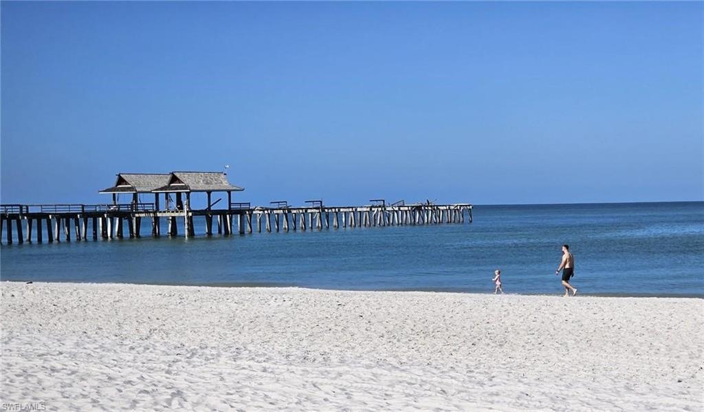 Dock area featuring a pier and view of water and beach