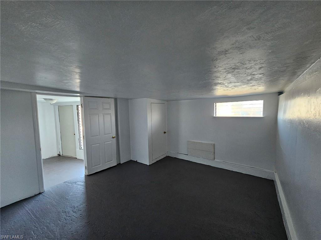 Basement with dark carpet and a textured ceiling