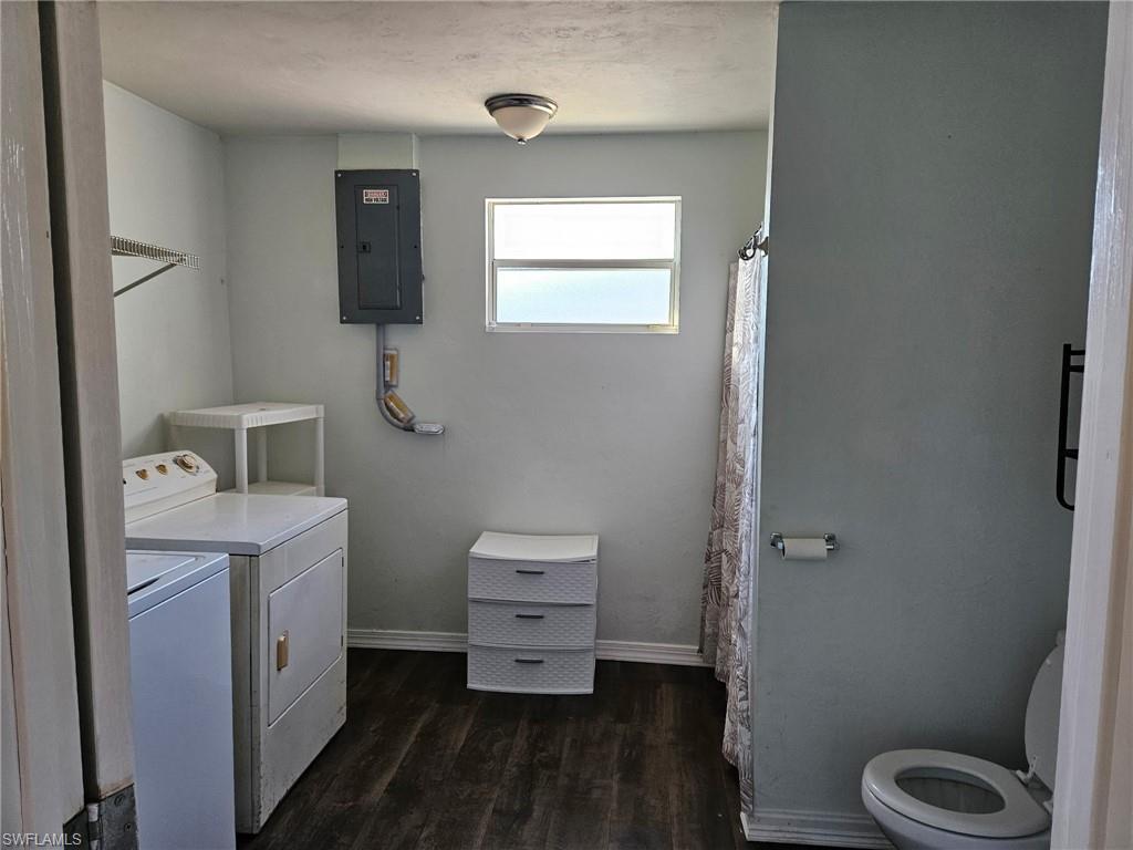 Laundry room with electric panel, dark wood-style flooring, and washer and dryer