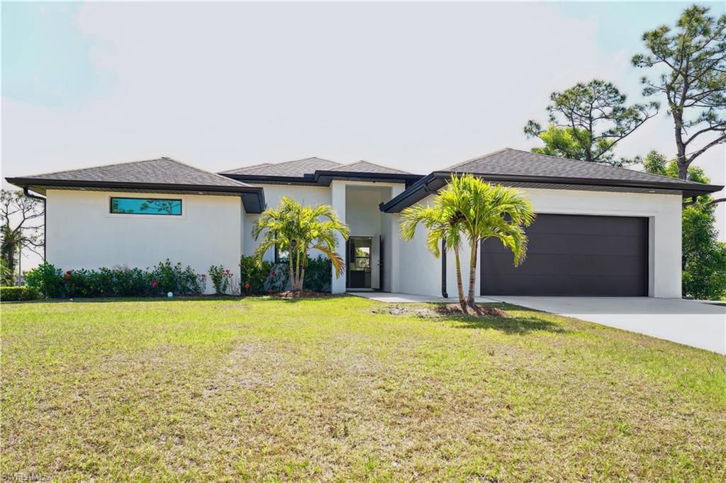 Prairie-style house featuring a front yard, concrete driveway, a garage, and stucco siding
