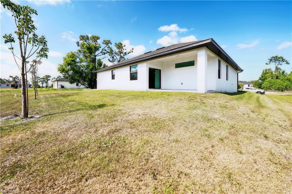 Rear view of house with a yard, stucco siding, and a patio area
