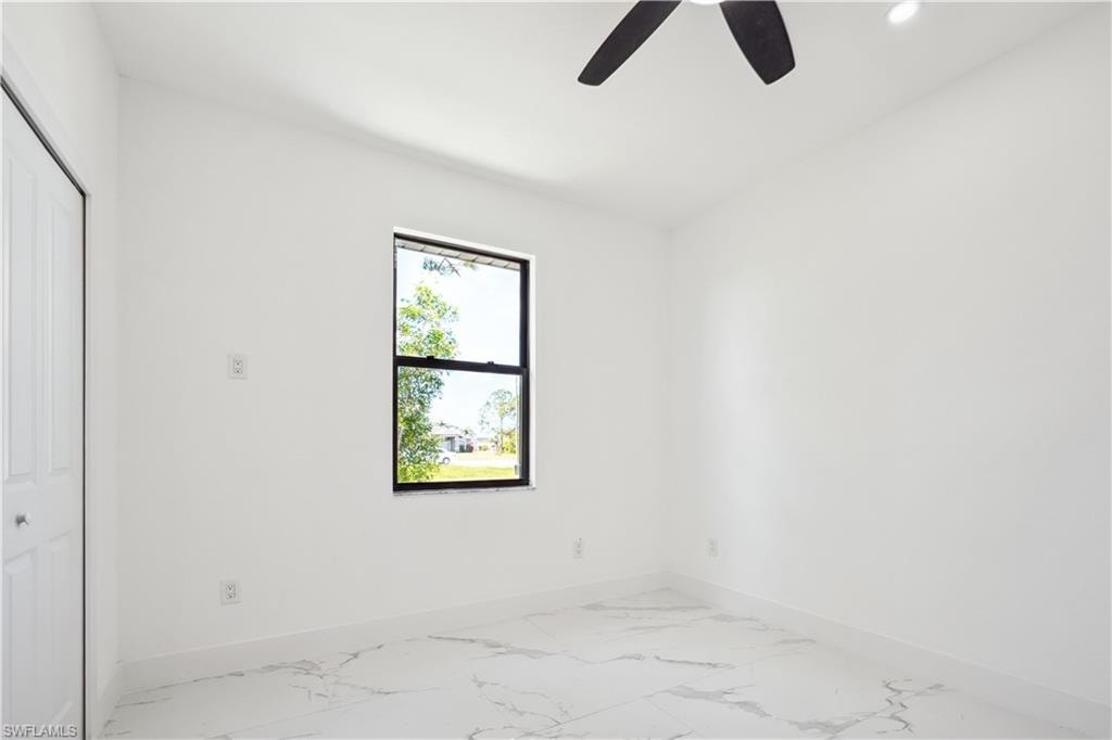Unfurnished bedroom with light marble finish floors, a closet, and a ceiling fan