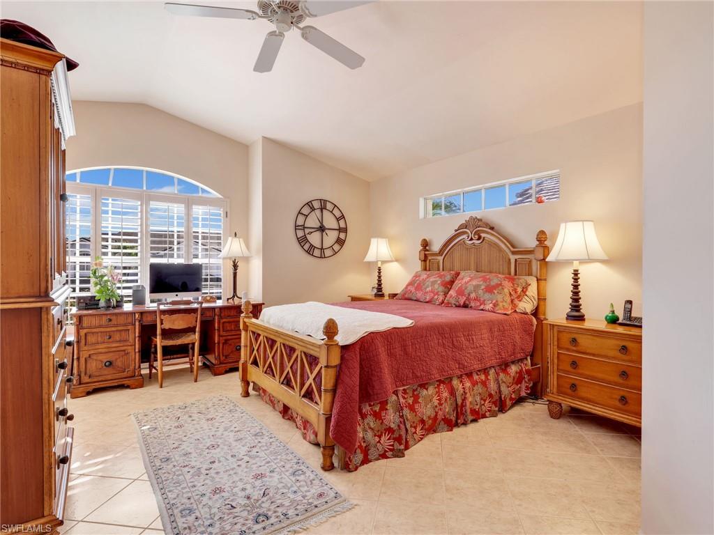 Bedroom featuring multiple windows, a ceiling fan, vaulted ceiling, a desk, and light tile patterned flooring