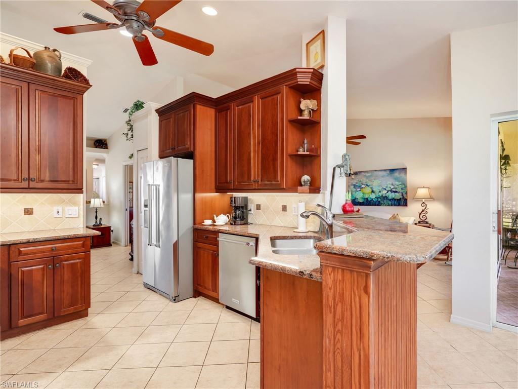 Kitchen with 42" custom Walnut cabinetry, backsplash, stainless steel appliances, granite countertops, decorative light fixtures, and a peninsula