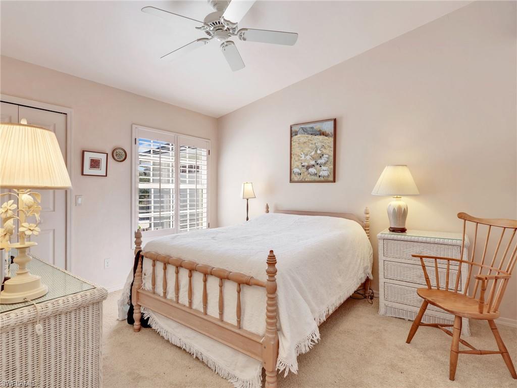 Carpeted bedroom featuring ceiling fan and lofted ceiling