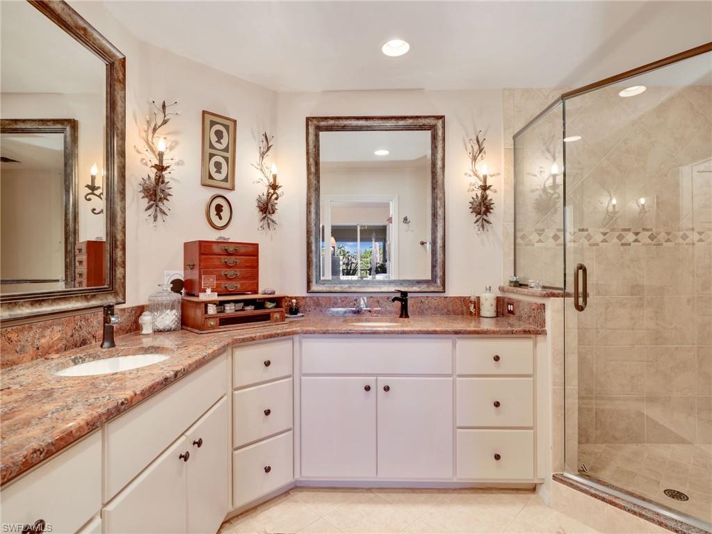 Full bathroom featuring double vanity, a stall shower, custom cabinetry, and recessed lighting
