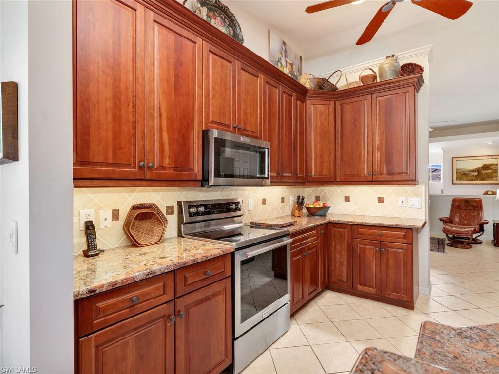 Kitchen with 42" custom Walnut cabinetry, backsplash, stainless steel appliances, granite countertops, decorative light fixtures