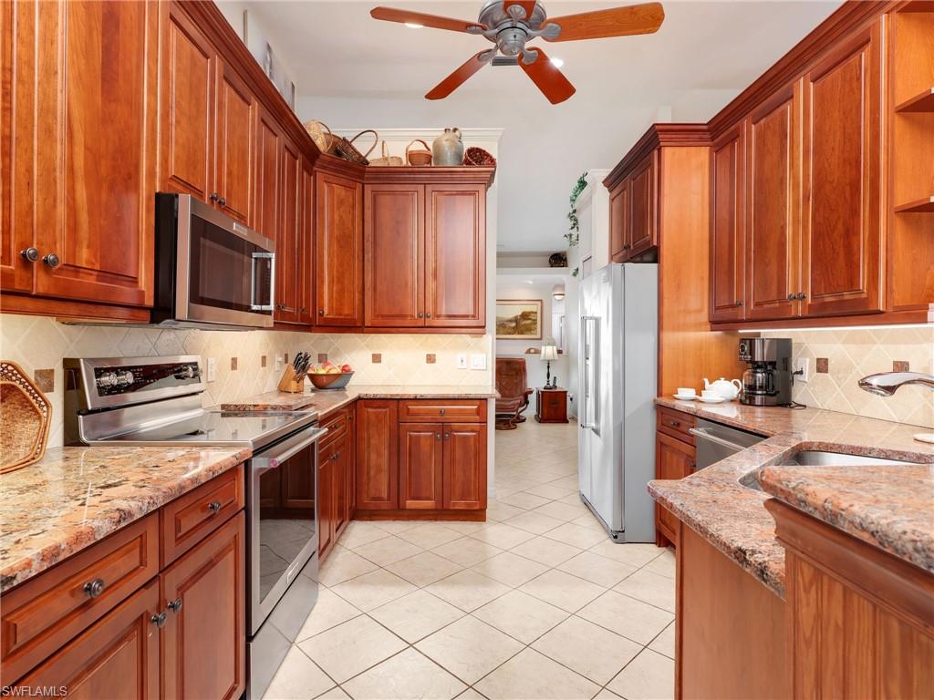 Kitchen with 42" custom Walnut cabinetry, backsplash, stainless steel appliances, granite countertops, and decorative light fixtures