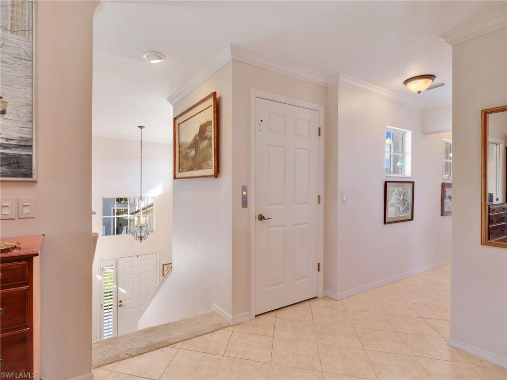 Elevator Door, Hall with ornamental molding, light tile patterned floors, and a chandelier