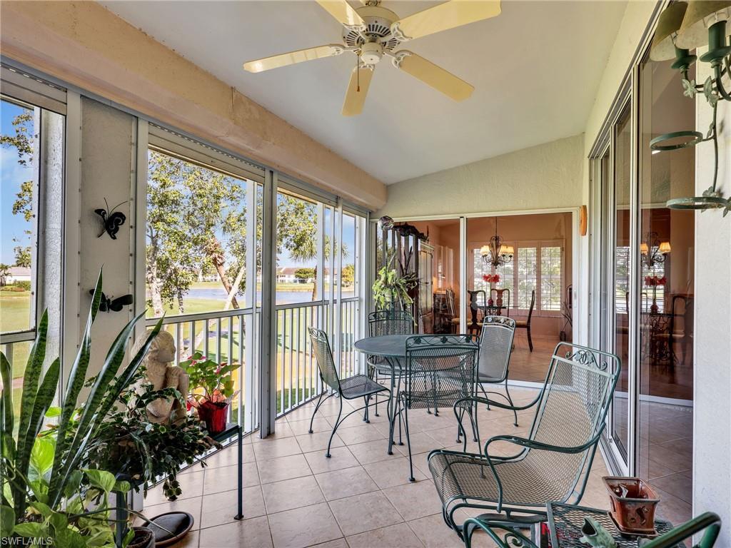 Sunroom featuring vaulted ceiling, tile patterned flooring, a water view, and a ceiling fan