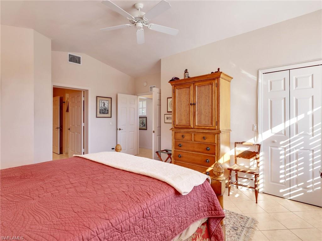 Bedroom with light tile patterned floors, vaulted ceiling, a closet, and ceiling fan