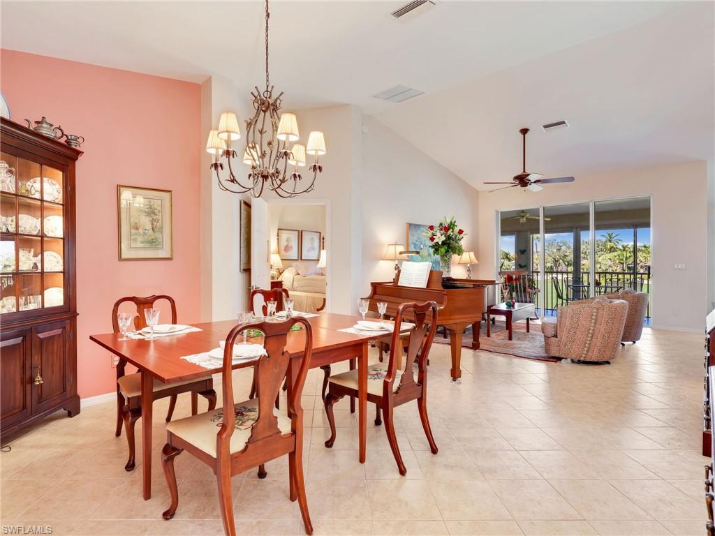 Dining area with lofted ceiling, ceiling fan, light tile patterned flooring, and a chandelier