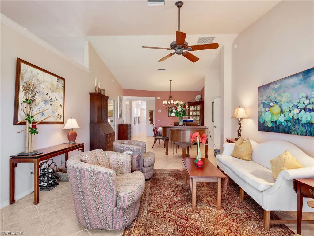 Living area with ceiling fan, light tile patterned flooring, and lofted ceiling