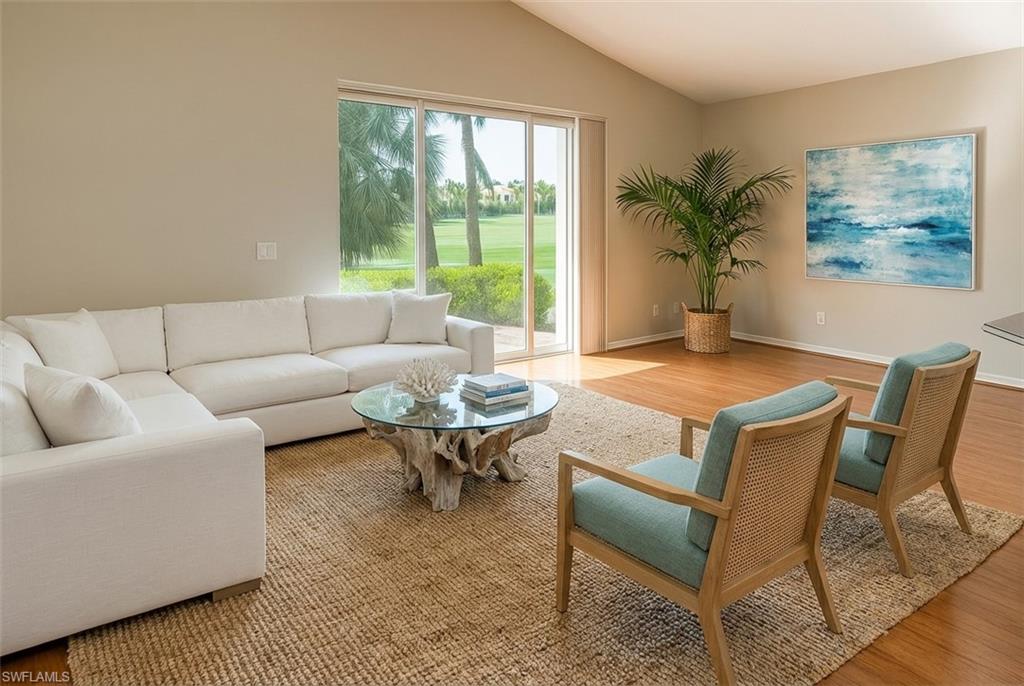 Living area featuring light wood-style flooring, vaulted ceiling, and view of golf course