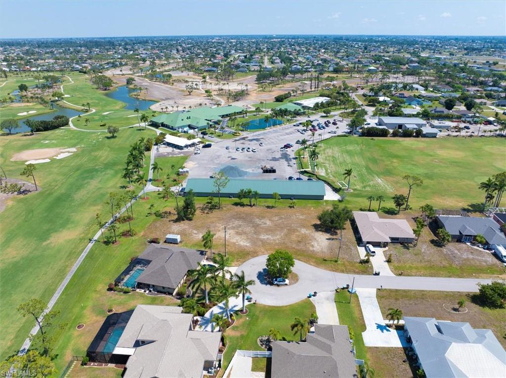 Aerial overview of property's location featuring a golf club, nearby suburban area, and a nearby body of water