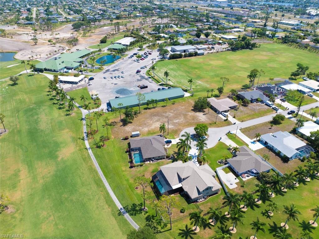 Aerial view of property and surrounding area featuring nearby suburban area, a local golf course, and a large body of water